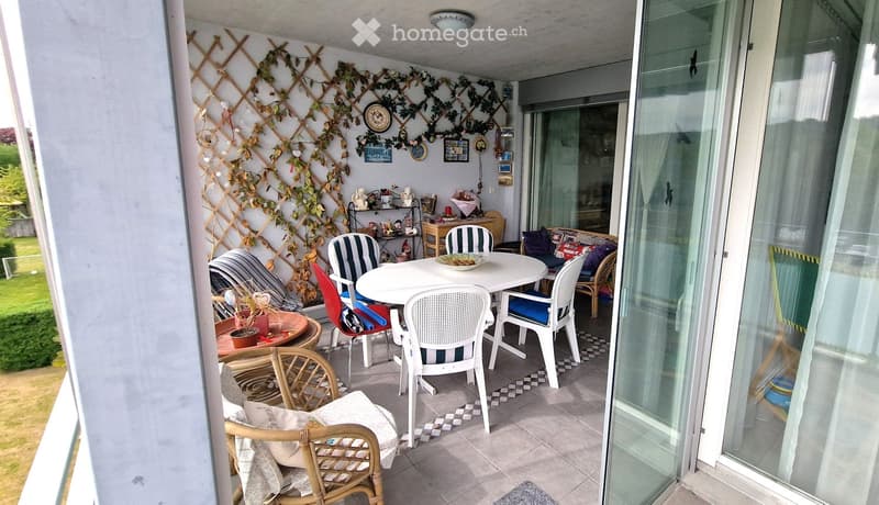 Balcony with table and chairs, decorative plants, glass doors, tiled floor