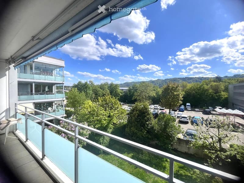 Balcony with railings, view of a parking lot, trees, and mountains