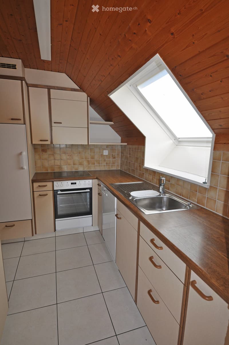 Modern kitchen with wooden cabinets, tiled backsplash, stainless steel sink, and built-in oven. Features a skylight window and wooden countertop.