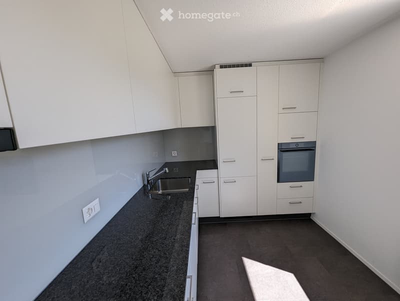 Modern kitchen with white cabinets, dark granite countertops, and stainless steel sink and oven.