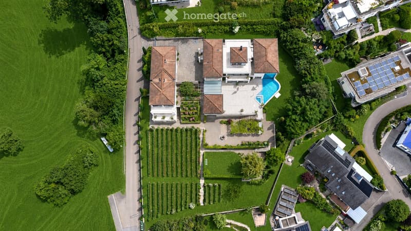 Aerial view of a large residential property with a swimming pool, garden, and multiple buildings.