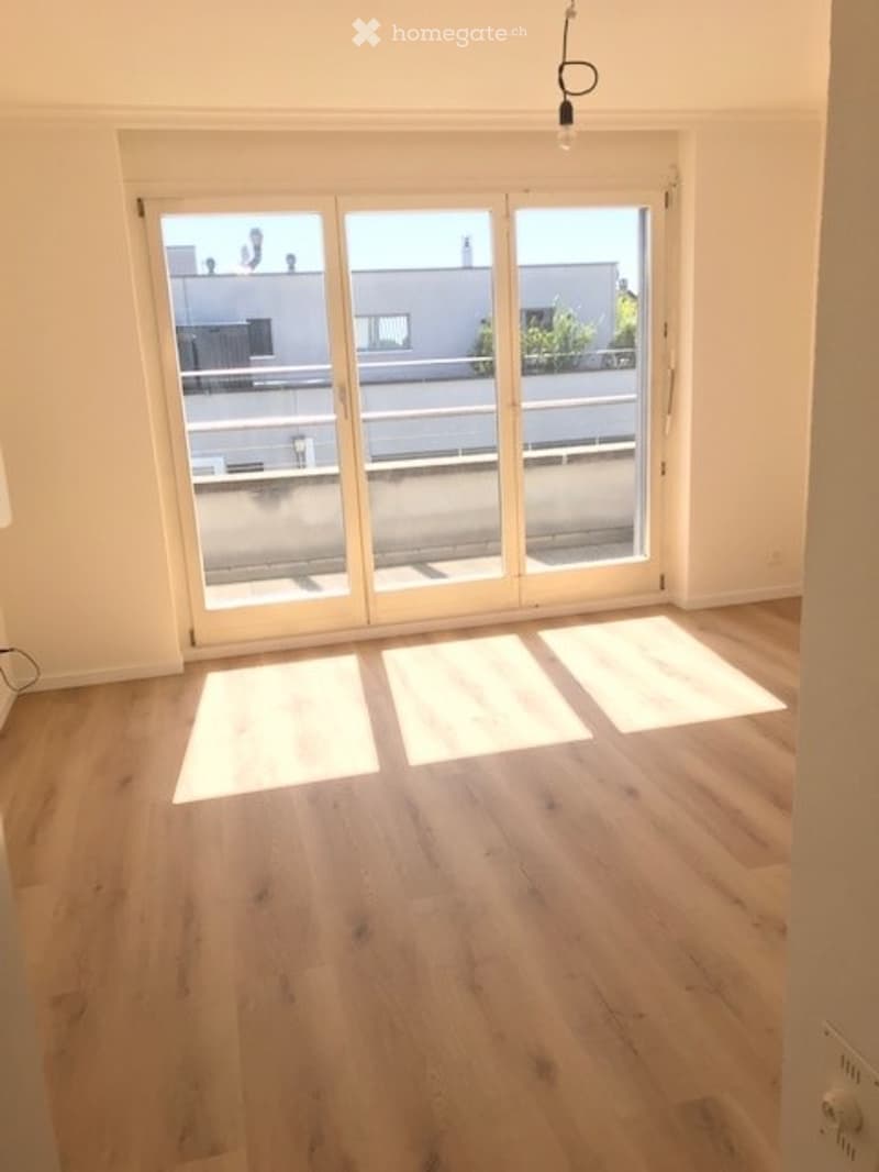 Empty room with wooden flooring and large sliding glass doors leading to a balcony.