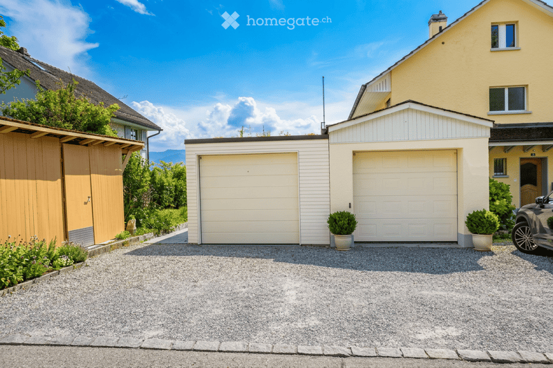 Two-story house with a double garage, yellow exterior, and well-maintained landscaping.