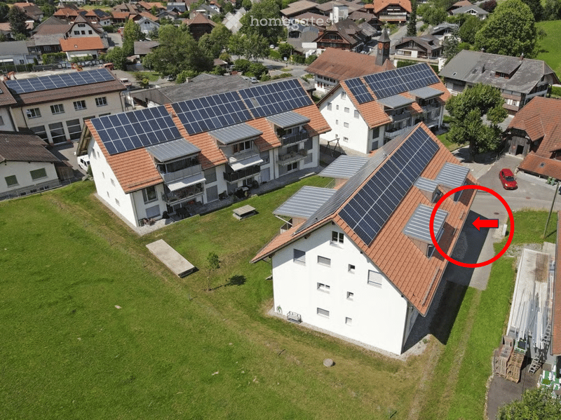 Aerial view of a residential area with multiple houses, solar panels on roofs, and a well-maintained lawn.