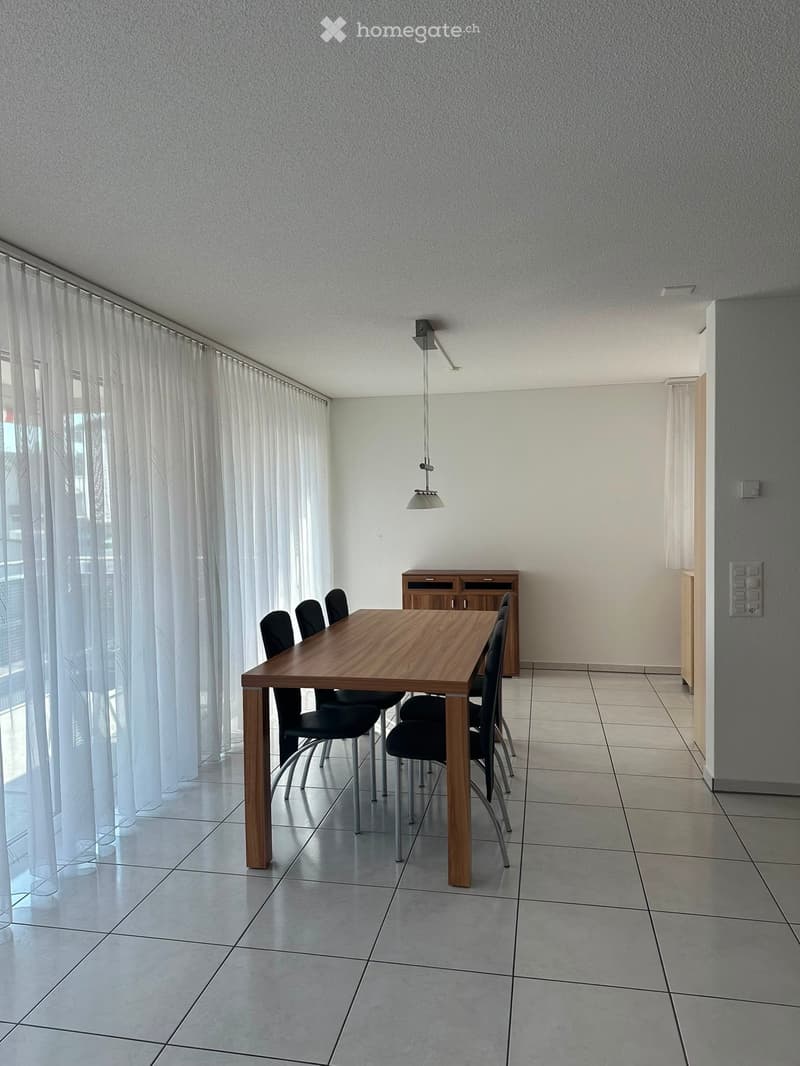 Dining room with a wooden dining table, six black chairs, a small wooden cabinet, and a hanging light fixture.