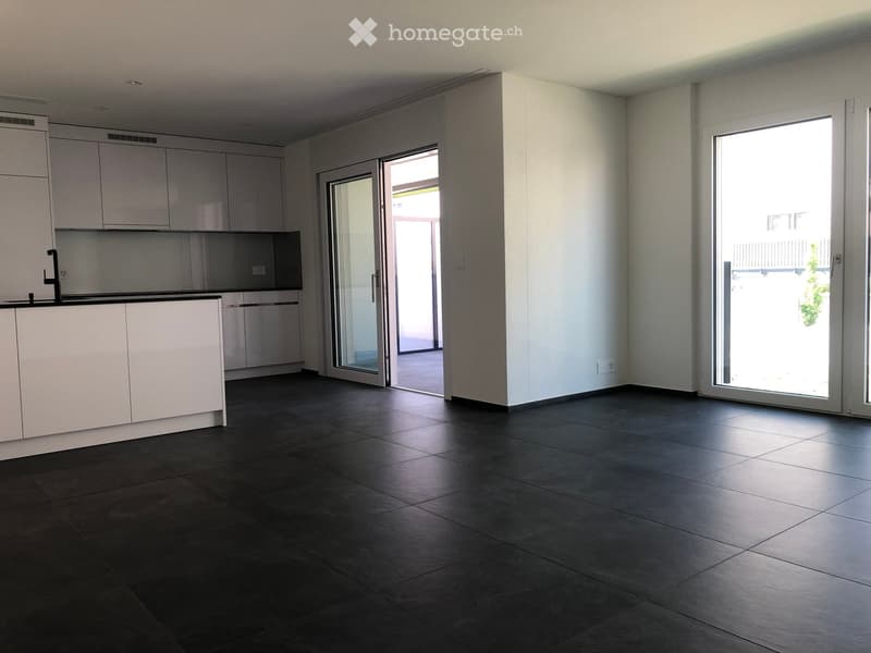 Empty kitchen with white cabinets, dark tiled floor, and large sliding glass doors leading to a balcony.