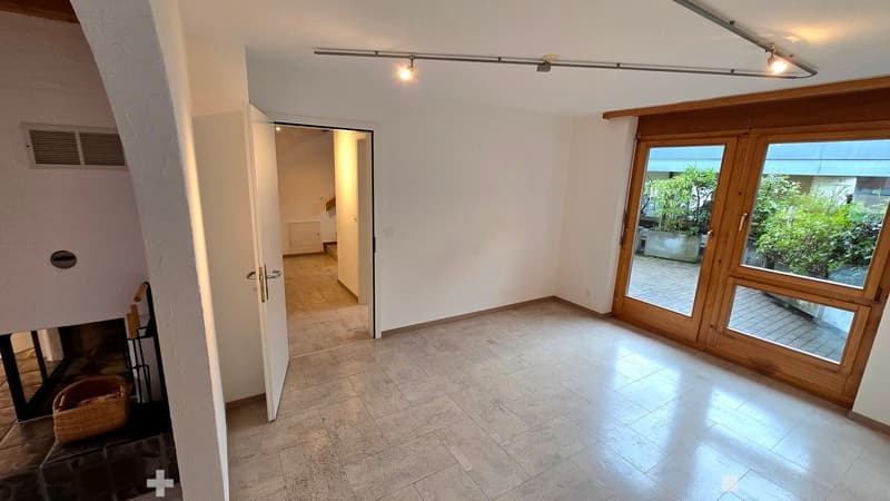 Bright hallway with tiled floor, white walls, large wooden sliding doors leading to a garden area, and a visible staircase leading upwards.