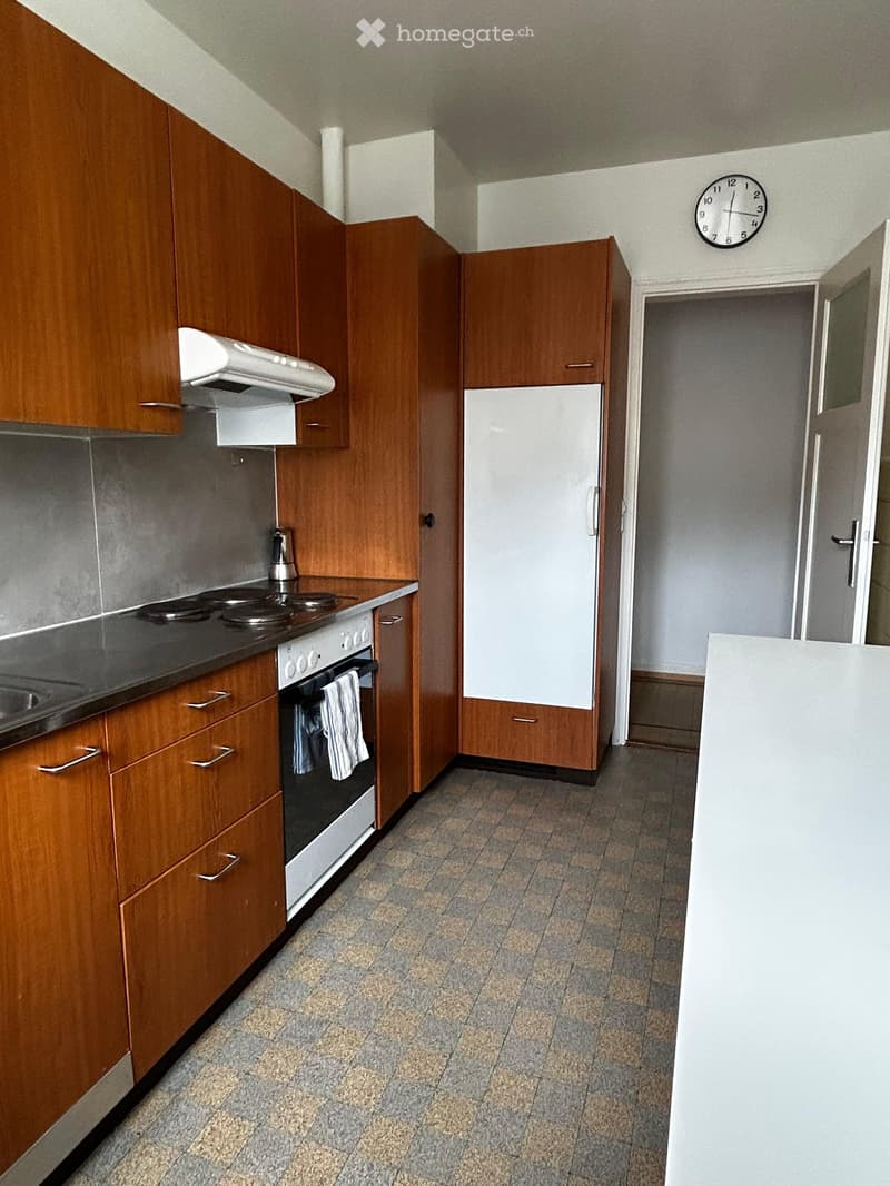 Modern kitchen with wooden cabinets, stainless steel appliances, and tiled flooring.