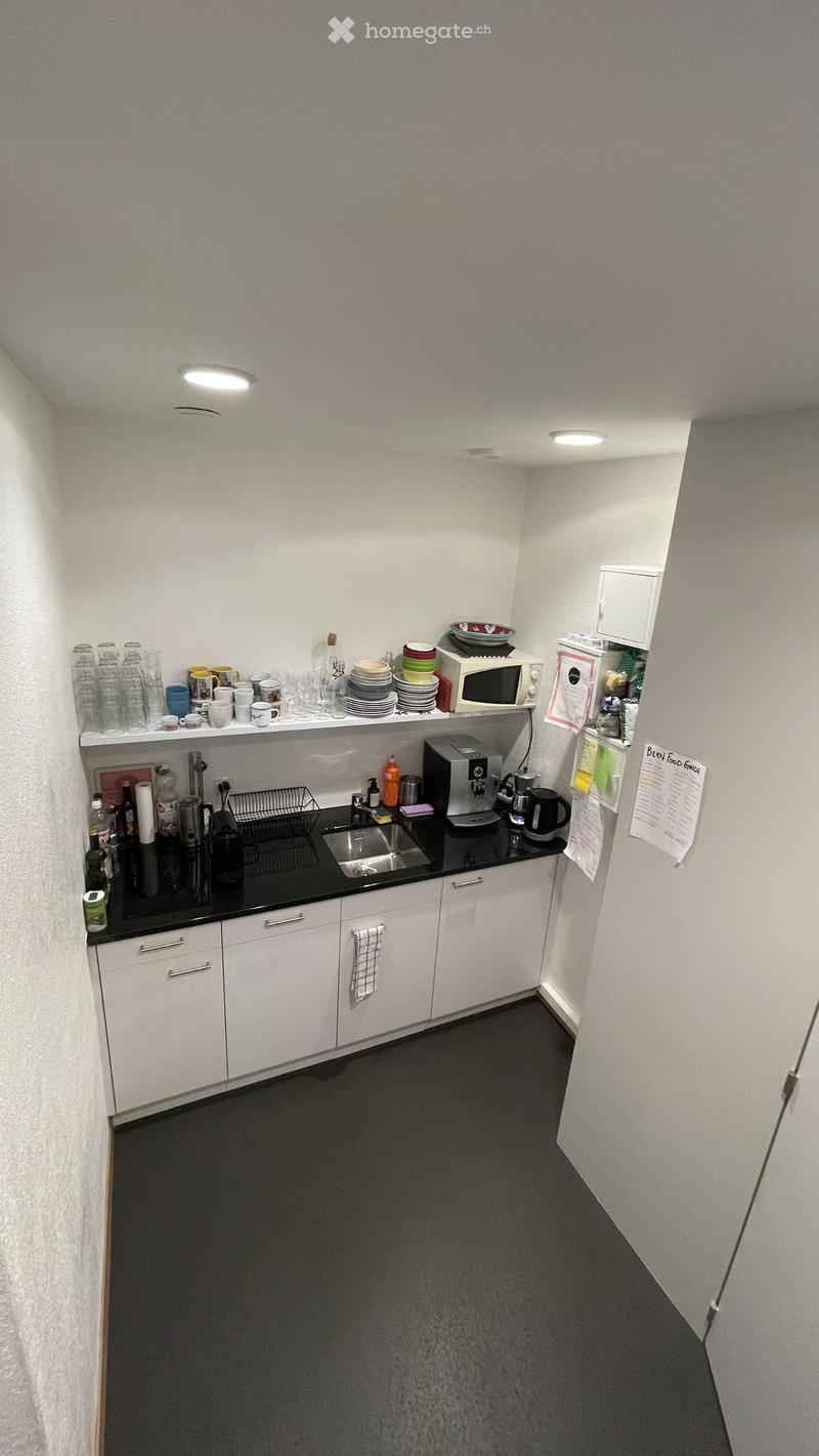 Modern kitchen with white cabinets, black countertops, and various appliances including a microwave, coffee maker, and sink.