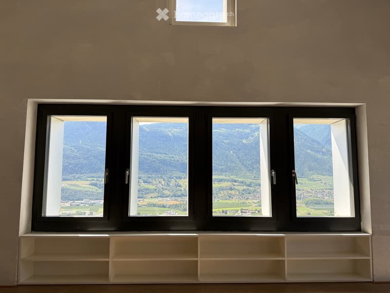 Empty room with large windows offering a scenic mountain view, white shelving unit below the windows.