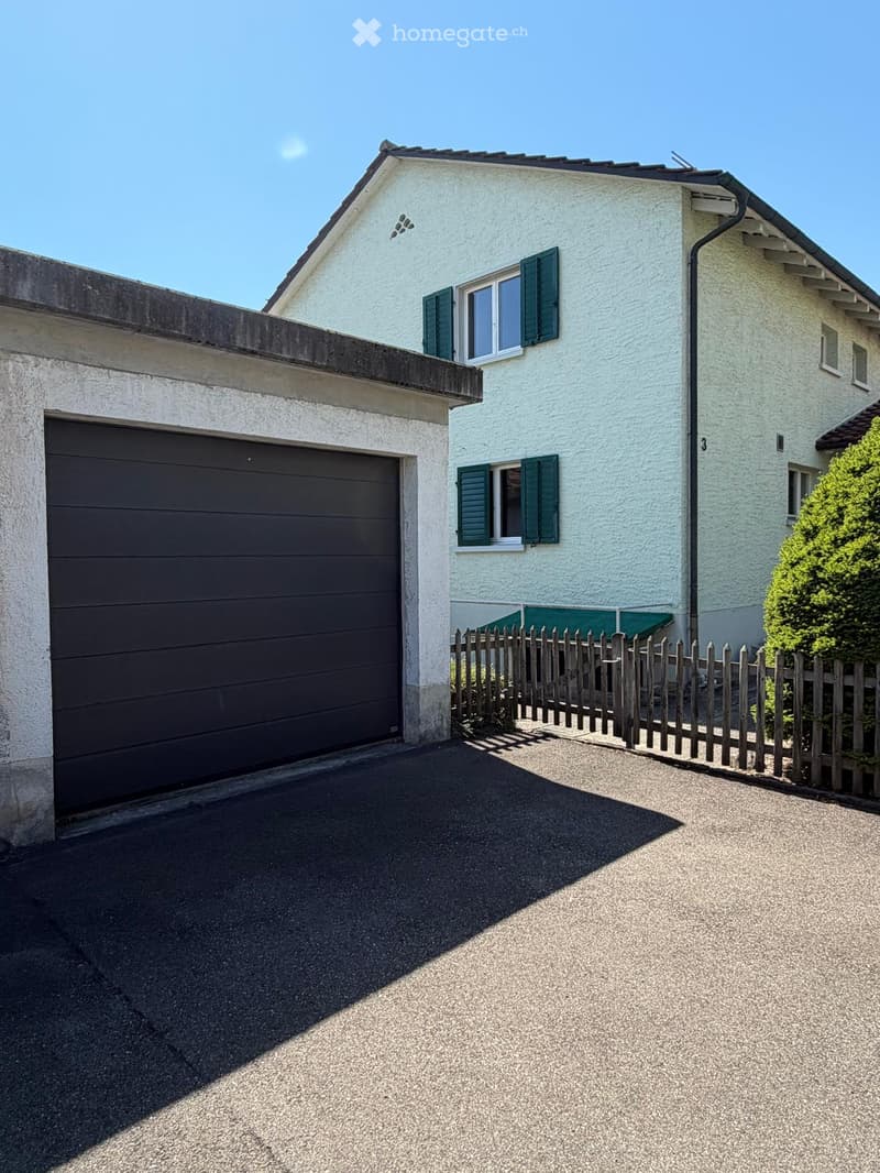 Two-story house with white exterior, green shutters, garage, and wooden fence.