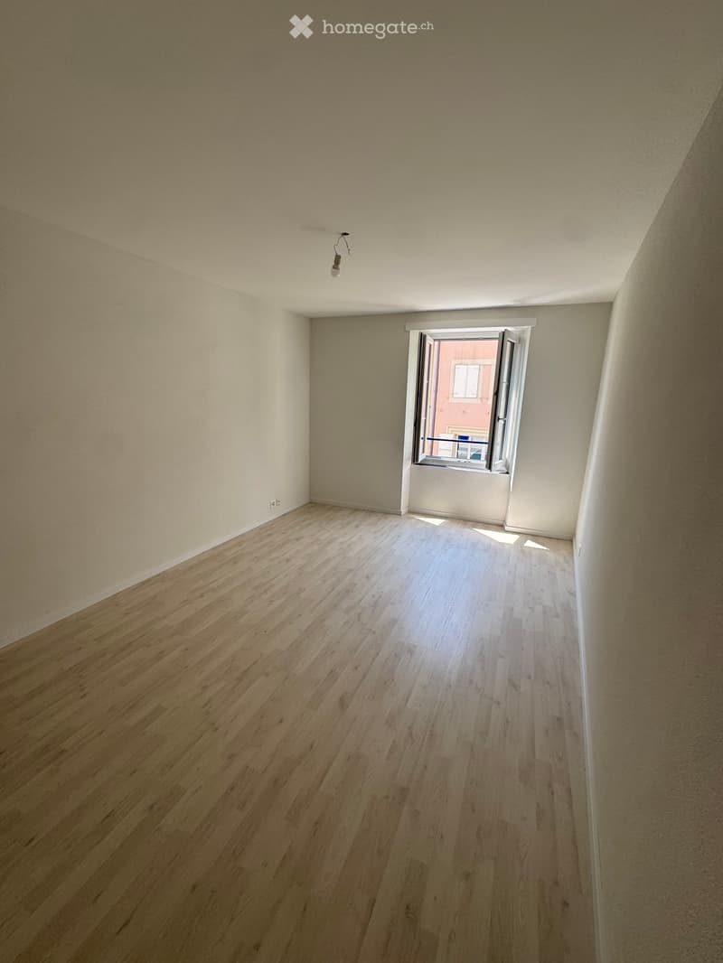 Empty room with wooden flooring, white walls, and a single window with white frame and blinds. No furniture or equipment present.