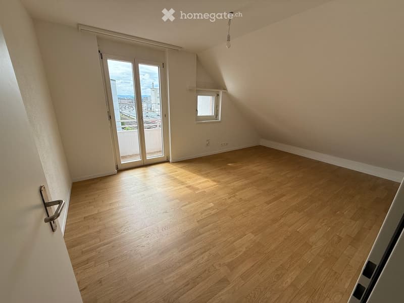Empty room with wooden flooring, large window, and sliding glass door leading to a balcony.