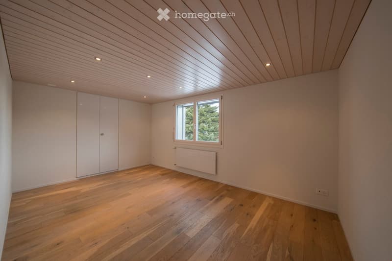 Empty room with wooden flooring, white walls, built-in closet, window with view, and recessed lighting.