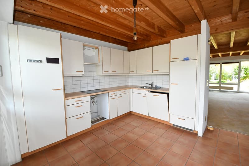 Bright kitchen with white cabinets, tiled walls, and a wooden ceiling. Features include a sink, faucet, dishwasher, and electric stove.