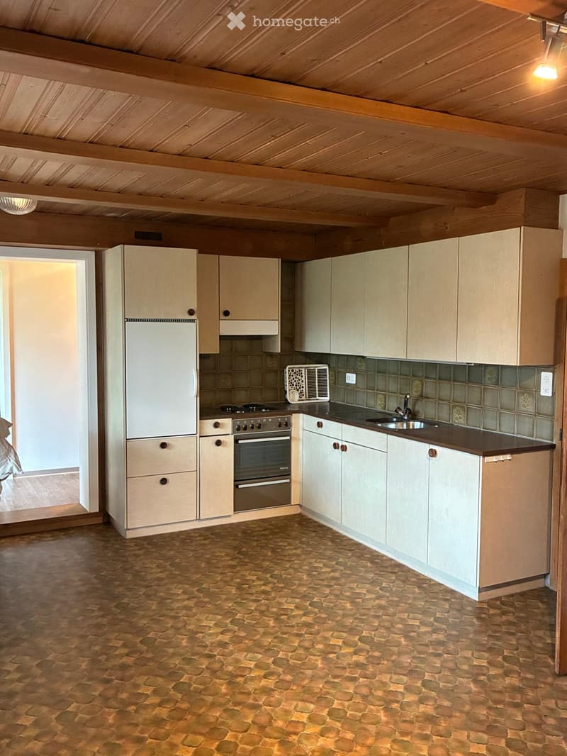 Bright kitchen with wooden cabinets, a stone-tiled floor, and modern appliances including a refrigerator, oven, and sink.