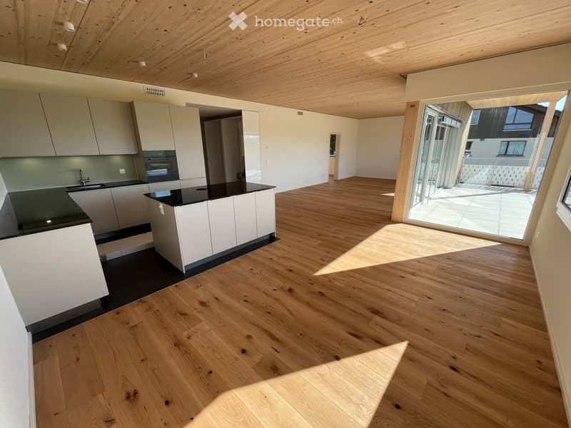Empty room, hardwood floors, white cabinets, modern kitchen with black countertops, sliding glass door to balcony