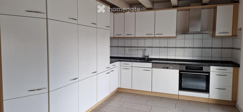 Modern kitchen with white cabinets, stainless steel appliances, and a black countertop.