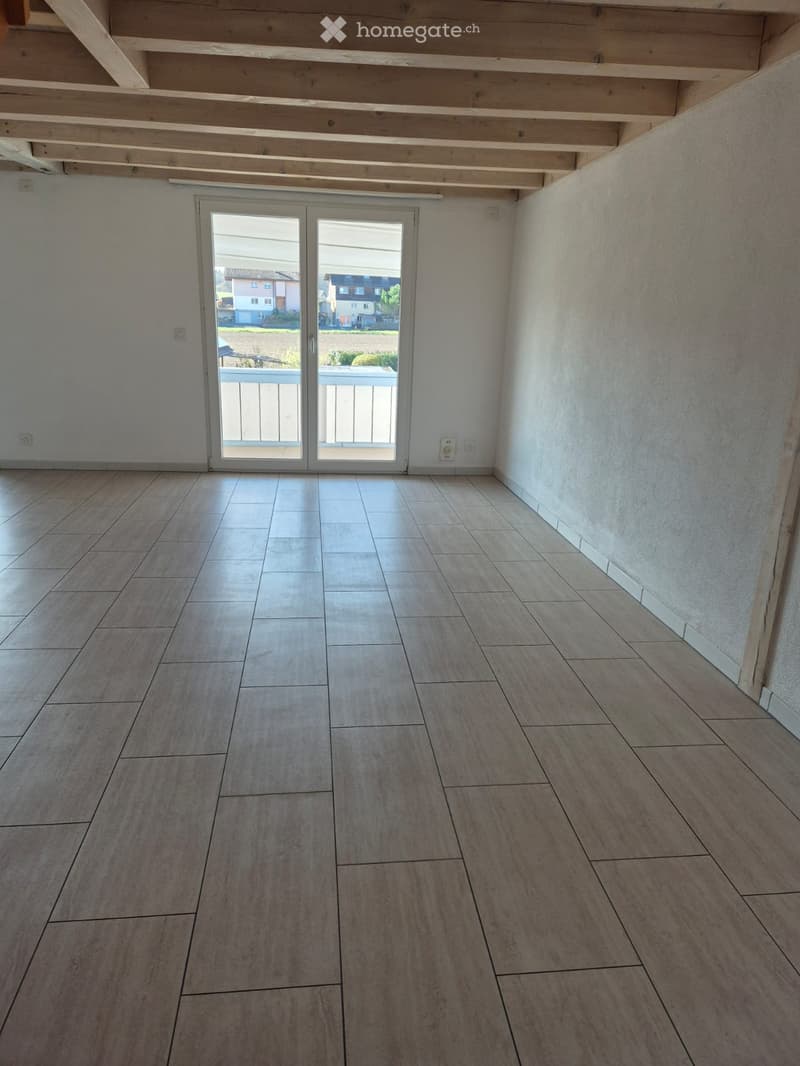 Empty room with tiled flooring, white walls, and a large sliding glass door leading to a balcony.