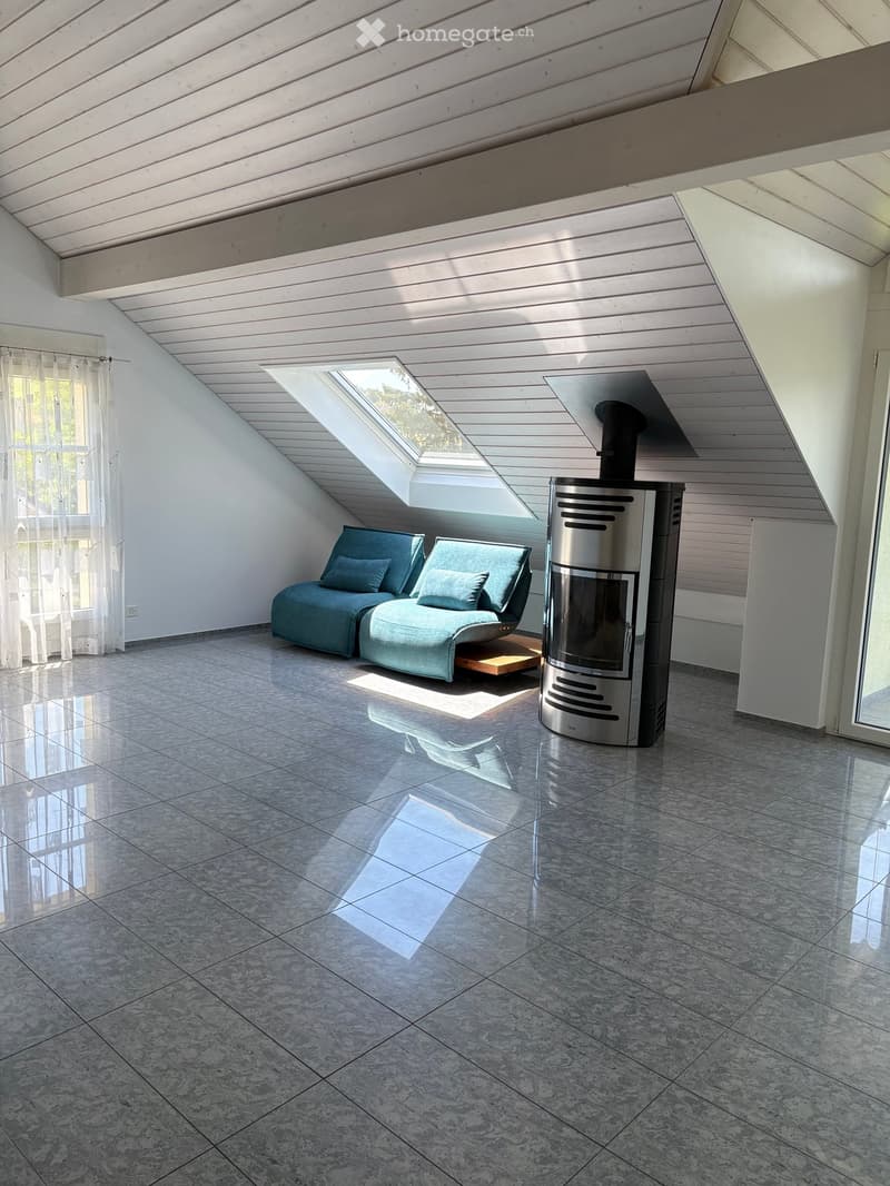 Modern living room with a sleek, contemporary fireplace, a comfortable sofa, and a small wooden table, featuring large windows and a skylight.
