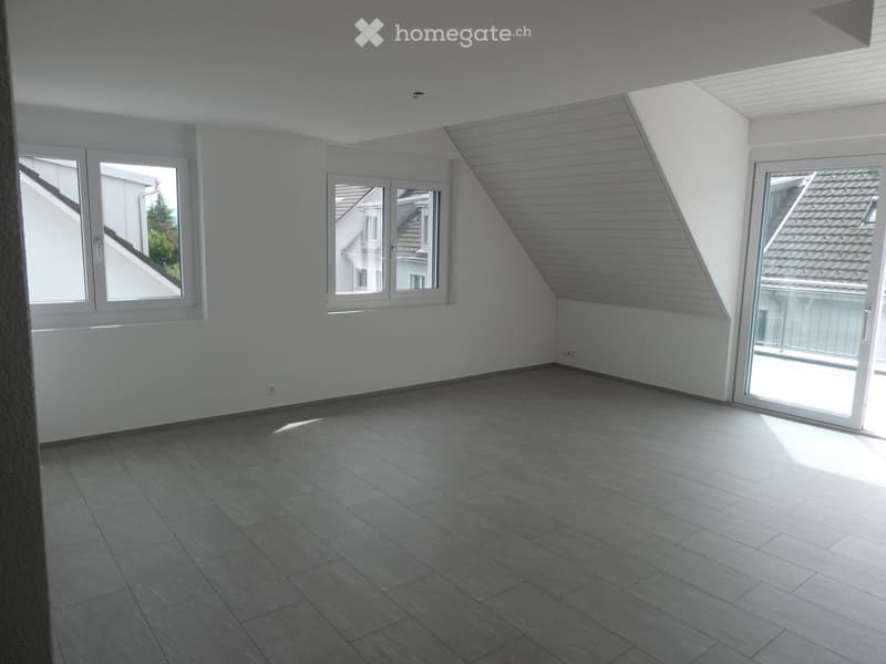 Empty room with white walls, grey tiled floor, large windows, and a sliding glass door leading to a balcony.