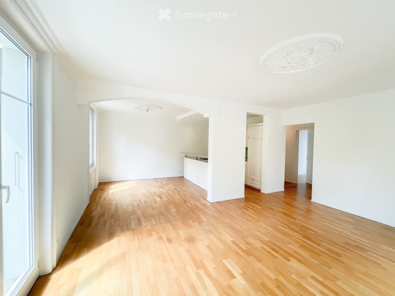 Empty room with light wooden flooring, white walls, and large windows. No furniture or equipment is present.