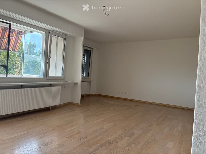 Empty room with wooden flooring, white walls, large windows, and radiators. No furniture or equipment present.
