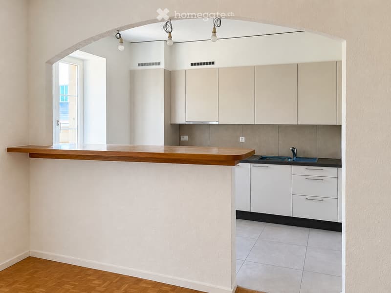 Modern kitchen with white cabinets, wooden countertop, sink, and tiled floor.