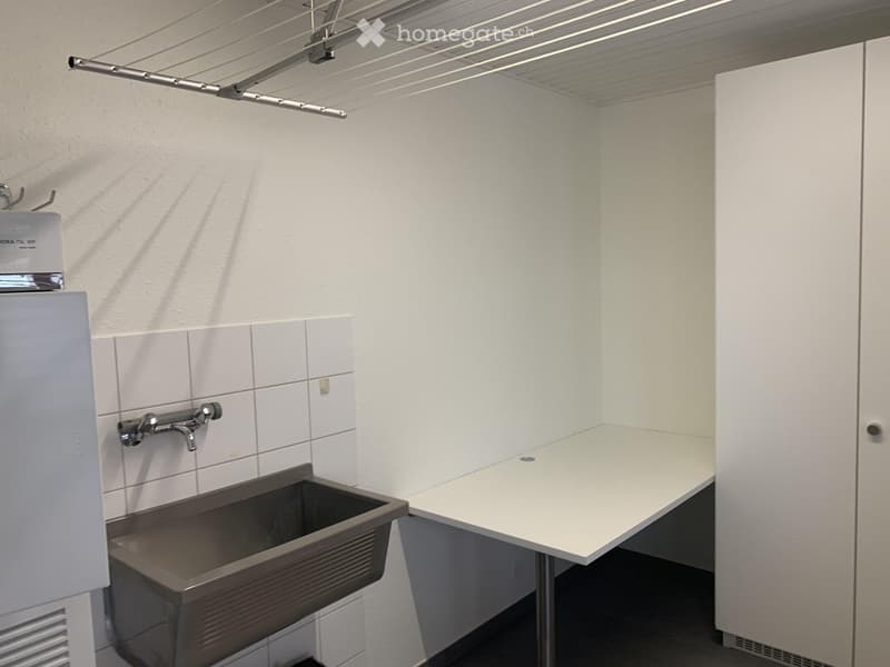 Clean, modern bathroom with a white tiled wall, a stainless steel sink, a faucet, and a white cabinet.