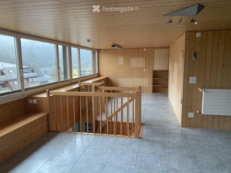 Bright hallway with wooden walls and ceiling, large windows, staircase with wooden railing, built-in bench seating, and a small shelf unit.