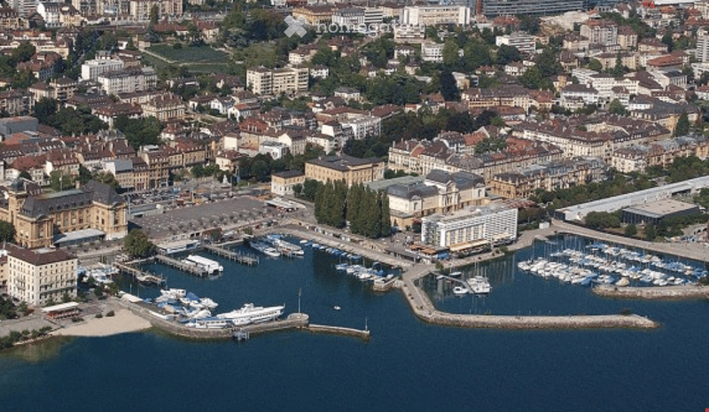 Aerial view of a cityscape with a waterfront featuring a marina with numerous docked boats, surrounded by buildings and structures.