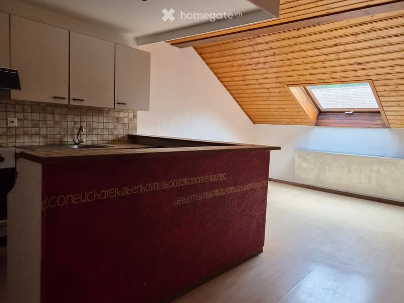 Modern kitchen with a wooden ceiling, skylight window, and a central island with a dark red countertop.