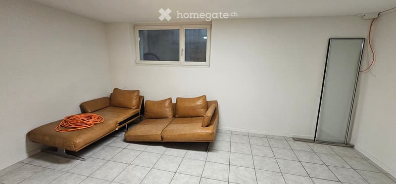 A modern living room with a brown leather sofa, a large mirror, and a tiled floor.