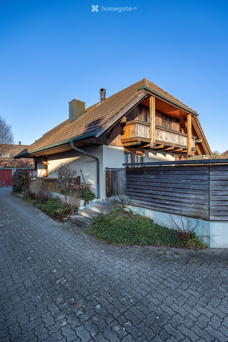 2 story house, brown roof, wooden balcony, wooden fence, brick driveway