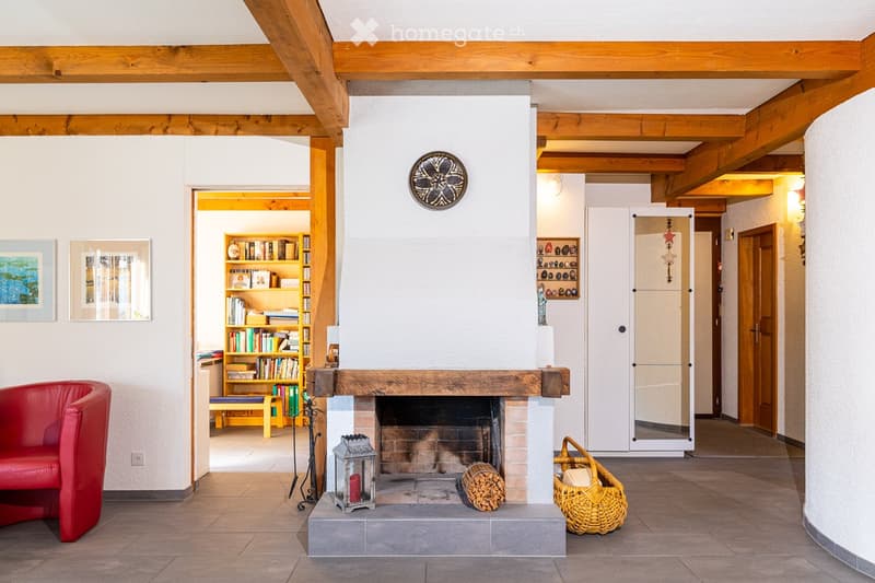 white walls, wooden beams, fireplace, red chair, wooden shelves, books, decorative items