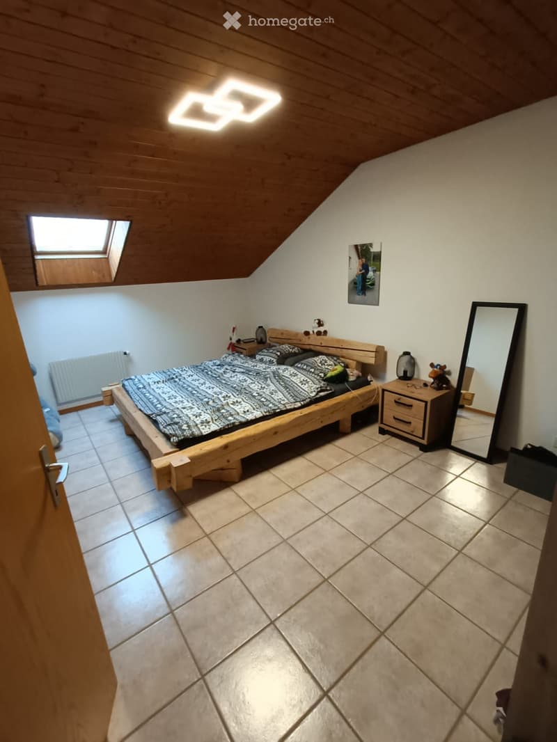 Cozy attic bedroom with wooden bed, nightstand, mirror, and skylight window.