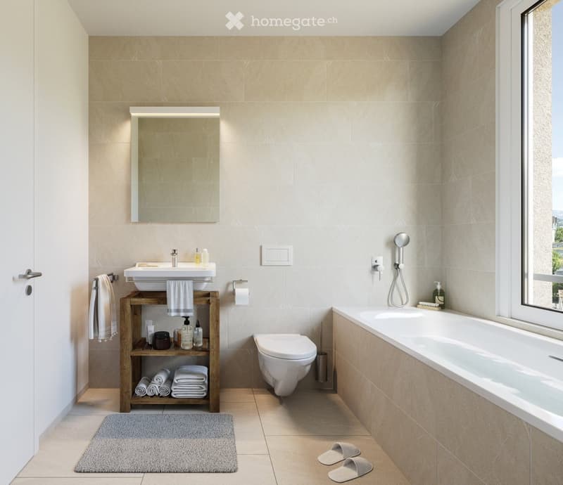 Modern bathroom with beige tiles, a wooden shelf holding towels and toiletries, a sink with a mirror, a toilet, and a bathtub with a showerhead. A grey bath rug and slippers are placed on the floor.