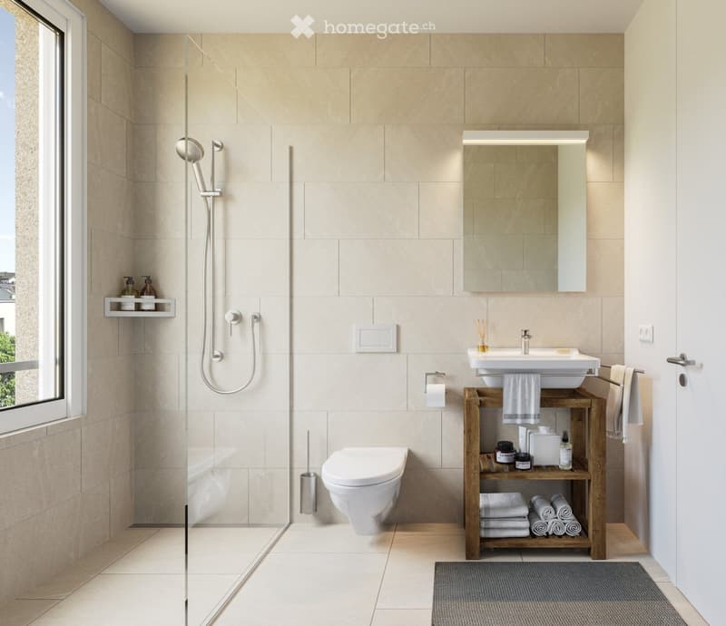 Modern bathroom with beige tiles, a glass-enclosed shower, a toilet, a sink with a wooden shelf holding towels and toiletries, and a mirror above the sink.