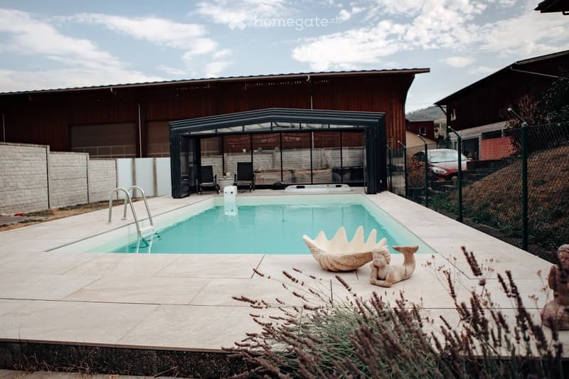 Private outdoor area with a swimming pool, surrounded by a covered patio, decorative sculptures, and lavender plants.