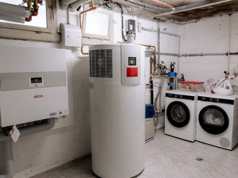 Utility room with a washing machine, dishwasher, and water heater, featuring exposed pipes and a small window.