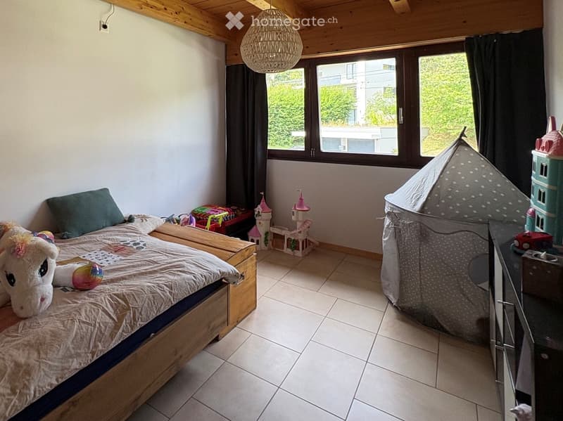 A cozy children's bedroom with a wooden bed, a large window, a tent, and various toys including a unicorn plush and a toy castle.