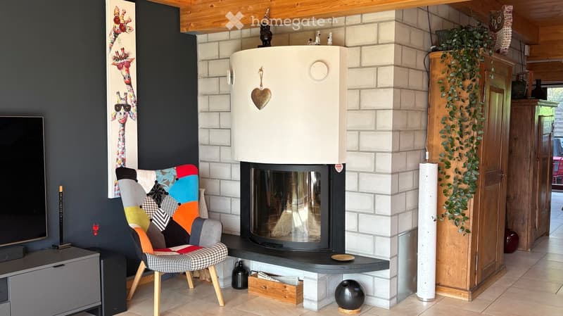 Living room with a modern fireplace, colorful sofa, wooden chair, decorative lamp, and artwork on the wall.