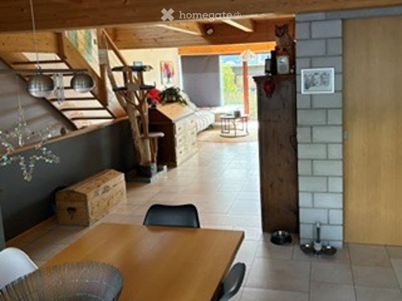 A cozy, rustic living room with wooden beams, a mix of modern and traditional furniture, and warm lighting.