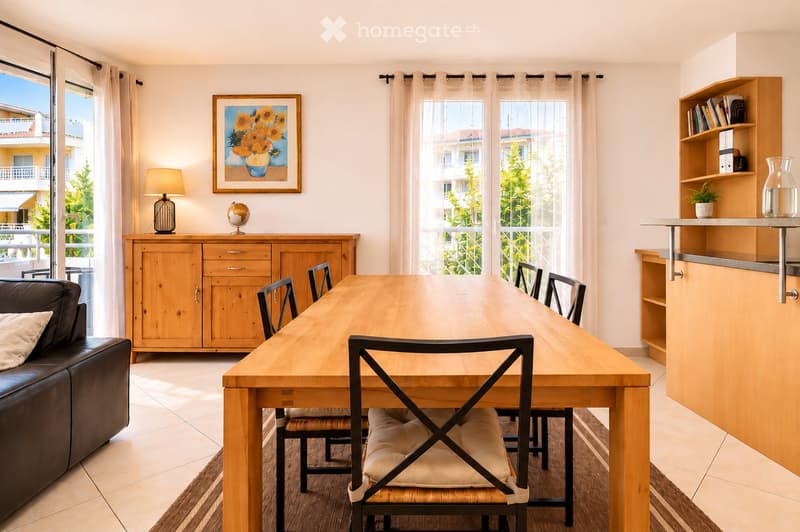 Bright, open living and dining area with large windows and sliding glass doors leading to a balcony. Features a wooden dining table with six chairs, a leather sofa, a wooden cabinet with drawers, a floor lamp, a globe, a picture frame, a bookshelf, and a
