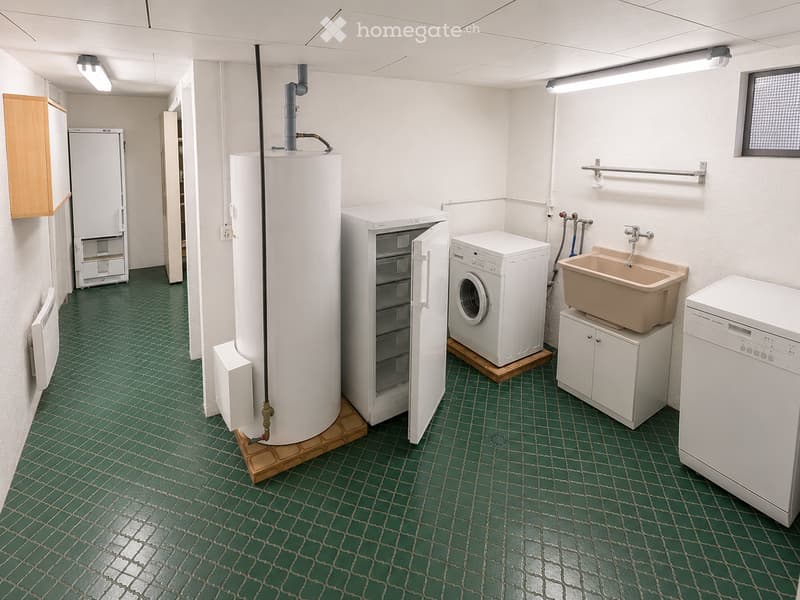 Utility room with green tiled floor, white walls, and various appliances including a washing machine, dishwasher, refrigerator, water heater, and sink.