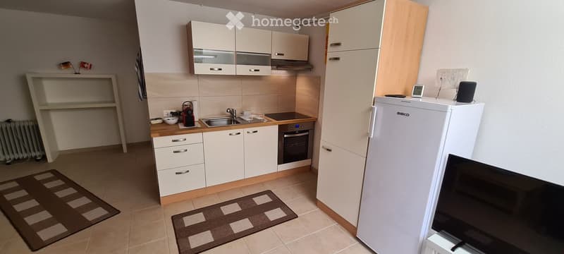 Modern kitchen with white cabinets, wooden countertops, stainless steel appliances, and two brown rugs on the floor.