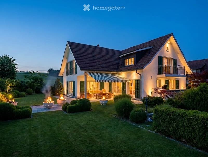 Two-story house with a modern design, featuring a well-maintained lawn, outdoor seating area, and fire pits.
