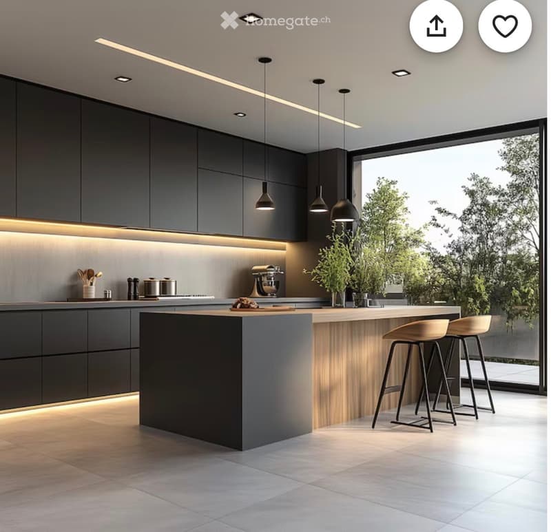 Modern kitchen with dark grey cabinets, a central island with wooden accents, pendant lights, and two bar stools. The space features a large window with a view of greenery outside.