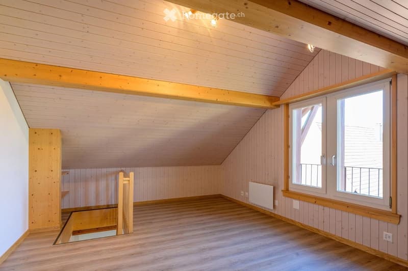 Empty room with wooden walls, ceiling, and floor, featuring a window with a view and a radiator below it.
