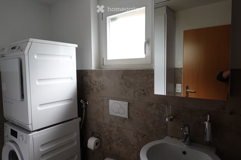 Bathroom with a washing machine and dryer, a sink, and a mirror.